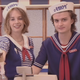 The faces of some people who are very happy to be dressed as sailors serving ice cream.